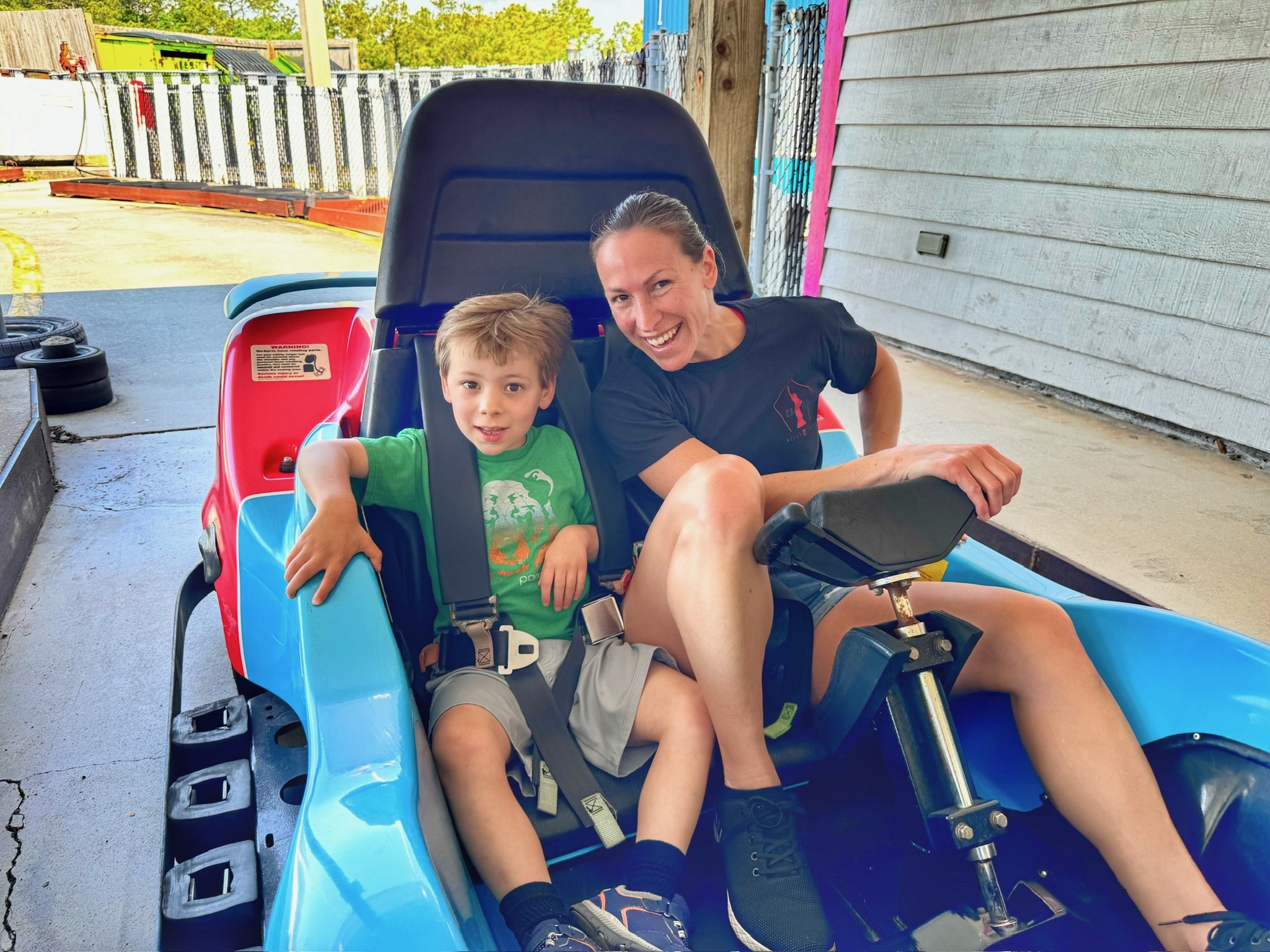 Noah riding a go-kart with his mom, both grinning