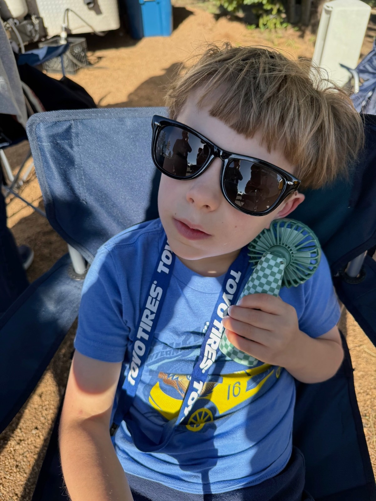 Noah in sunglasses on race day, holding a prize ribbon