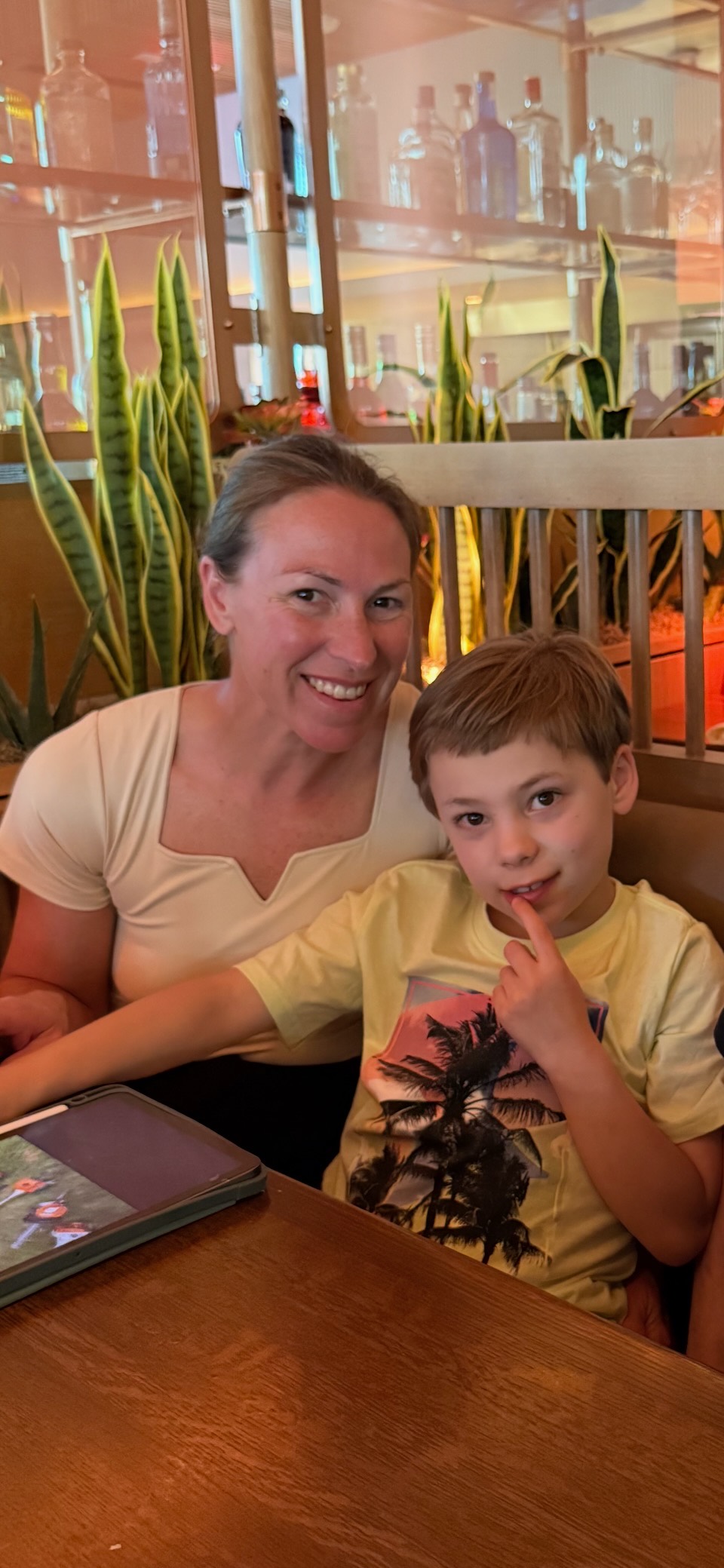 Noah leaning against his mom in a restaurant booth